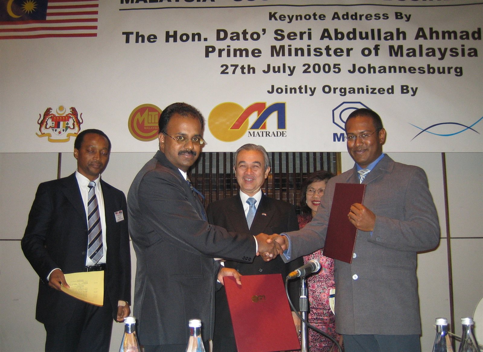 The exchange of signed documents at the Malaysia to South Africa business event in Johannesburg, 27 July 2005, with the Prime Minister of Malaysia standing behind.